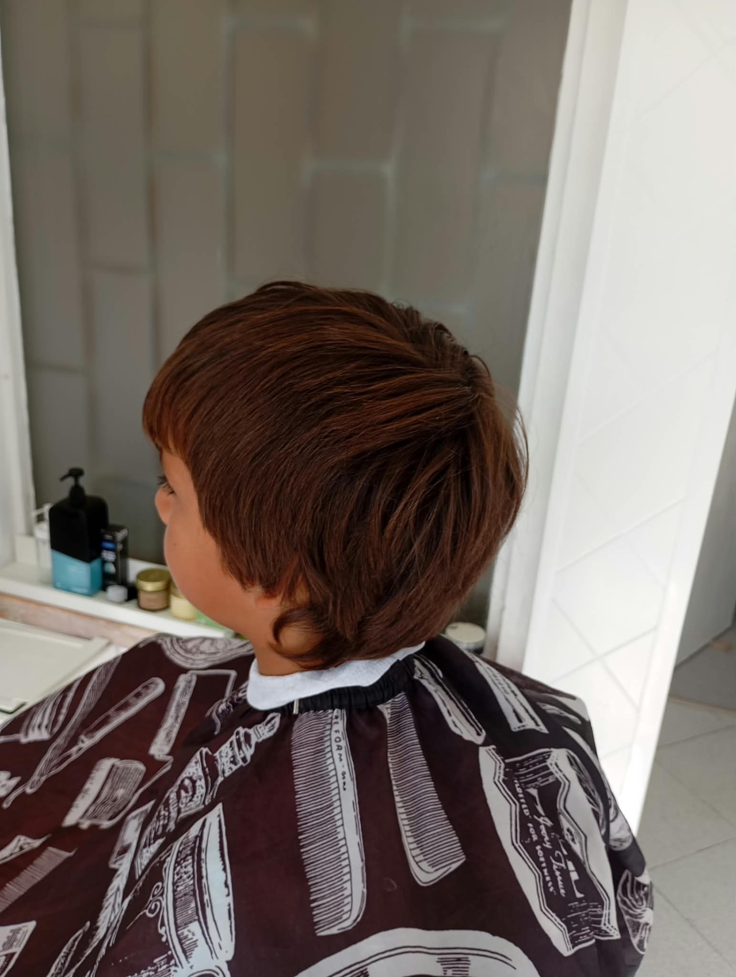 Criança ao chegar à barbearia com cabelo comprido a tapar a nuca