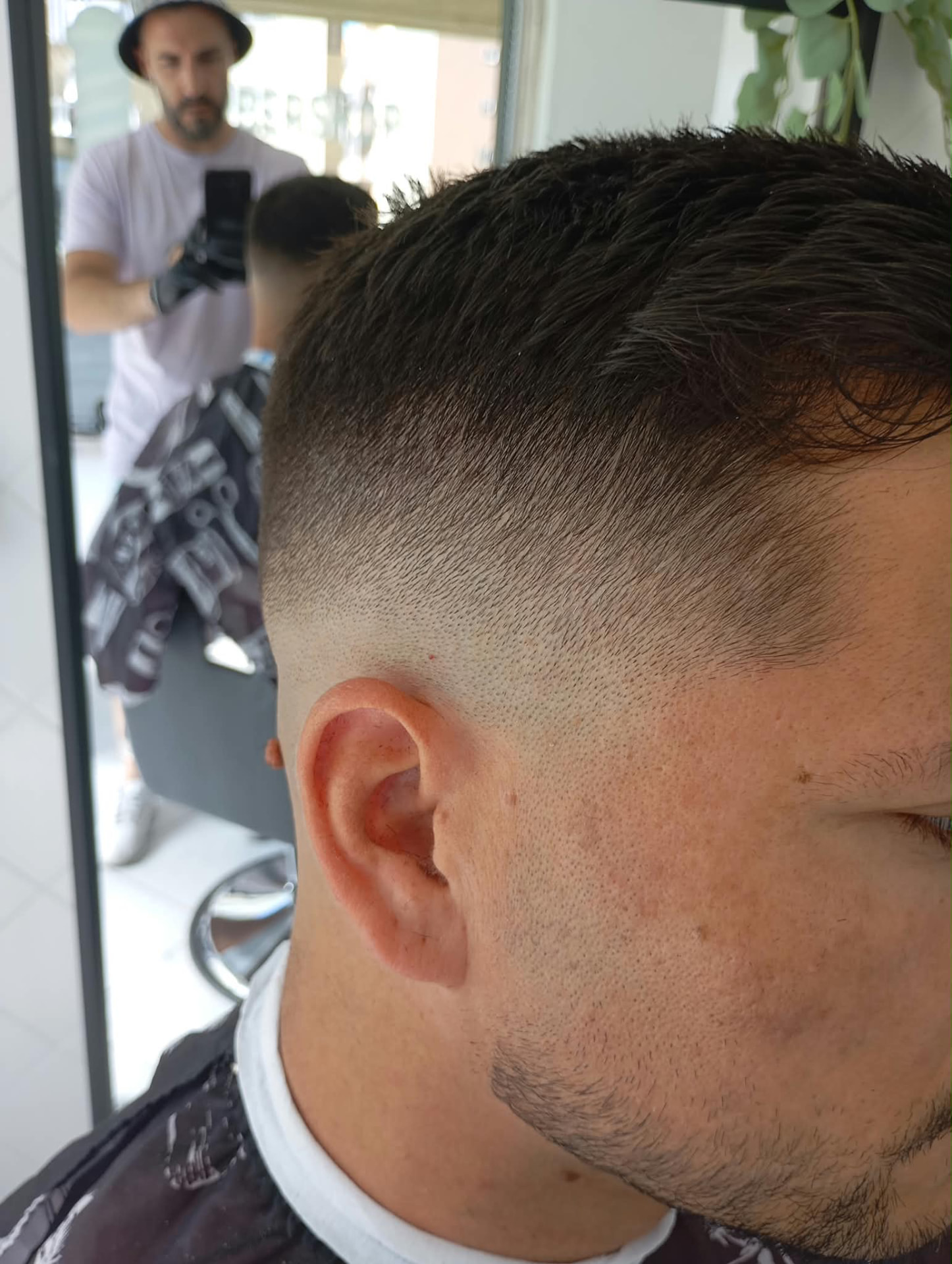 Degradê skin fade com risco natural e barba alinhada