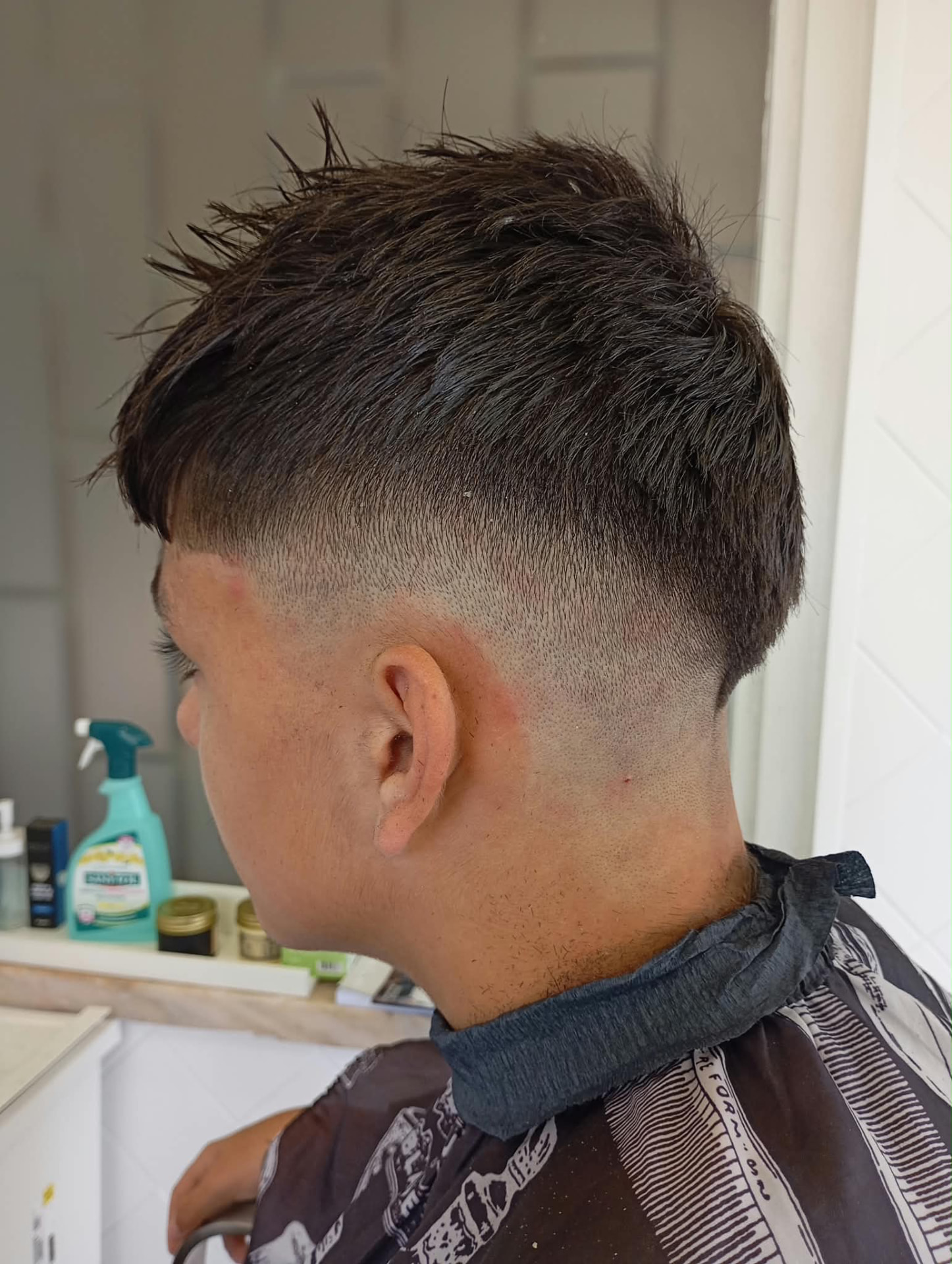 O mesmo cliente depois do corte, com degradê nas laterais e topo texturizado